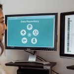 A woman looks at two computer screens containing information about the Manitoba Population Research Data Repository.