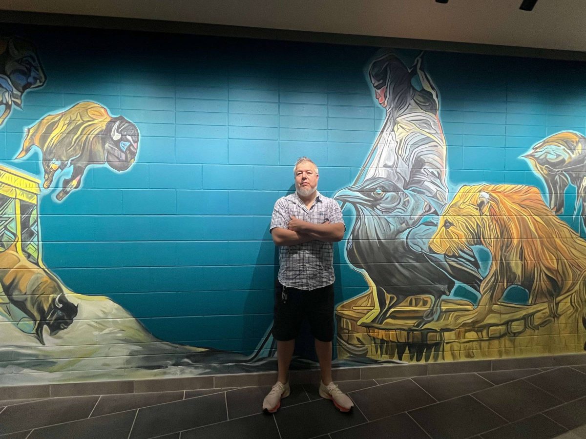 Artist posing in front of mural