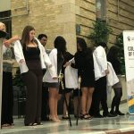 Students receive white coats from faculty, staff and mentors.