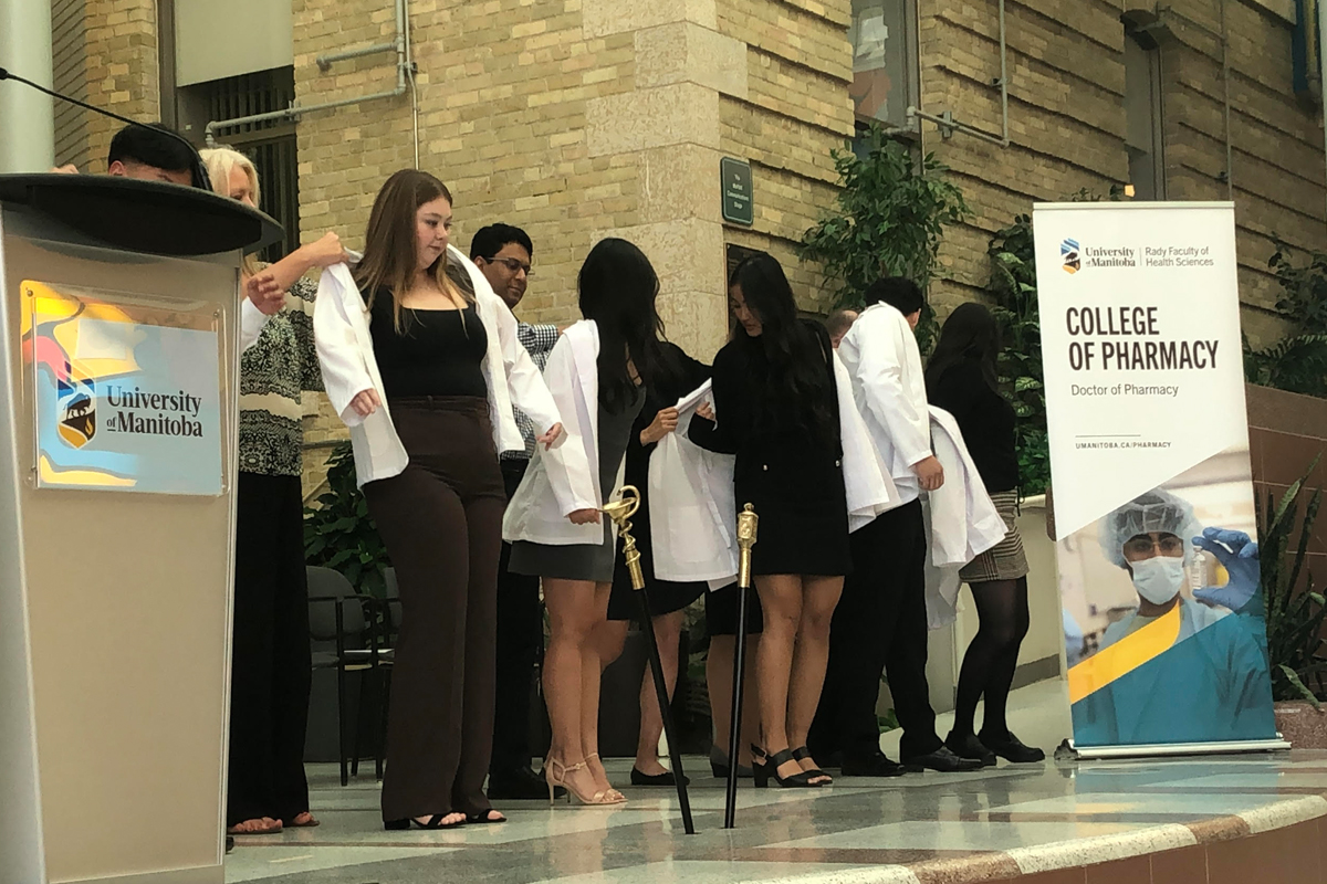 Students receive white coats from faculty, staff and mentors.