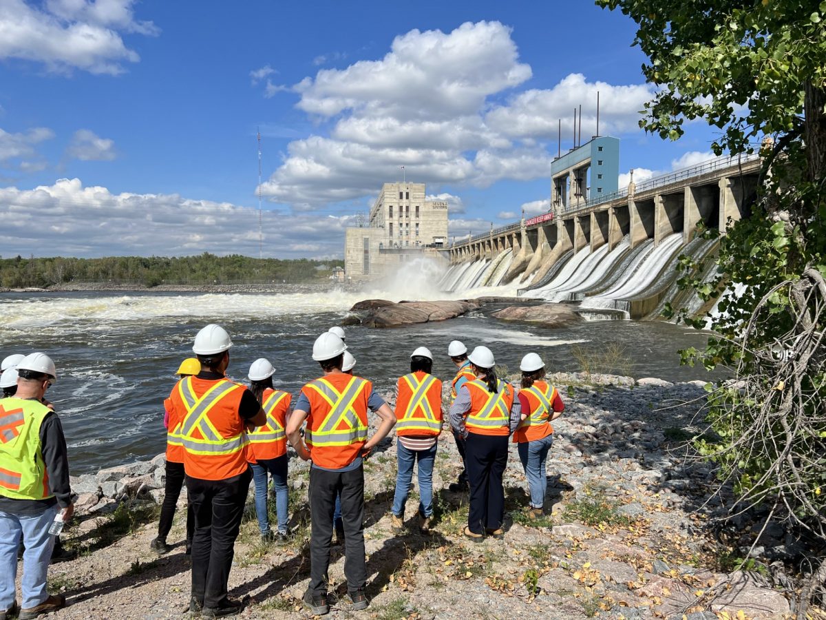 A group in safety vests and hard hats looking at a dam