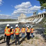 A group in safety vests and hard hats looking at a dam