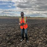 Dr. Afua Mante stands in a field holding cover crop