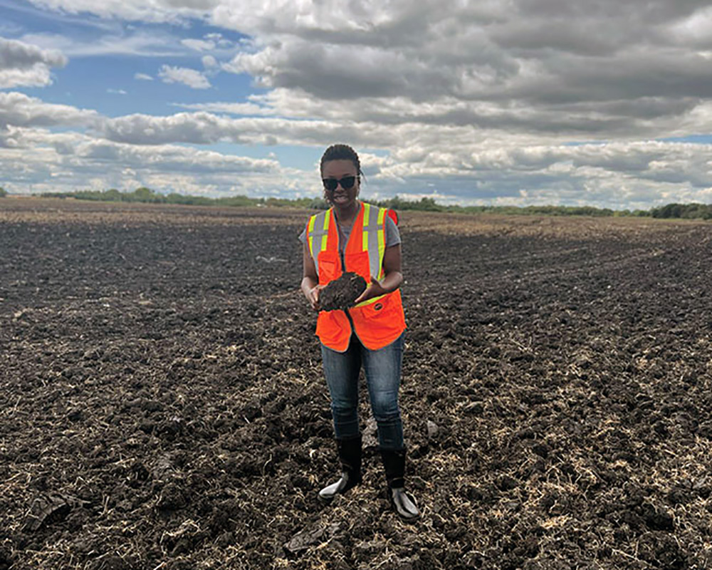 Dr. Afua Mante stands in a field holding cover crop