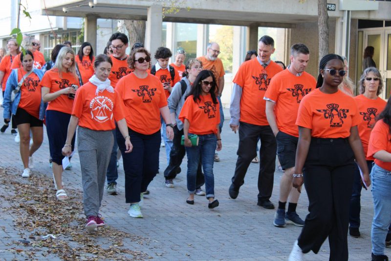 More than 24 people wearing orange T-shirts take part in the walk.