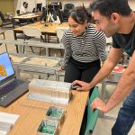 students looking at computer screen with model in front of them