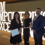 Photo of three people standing before UM Empowering Excellence sign