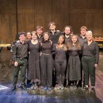 the percussion emsemble stands onstage - they are all dressed in black and smiling and looking at the camera. The names of everyone are listed in the caption from left to right