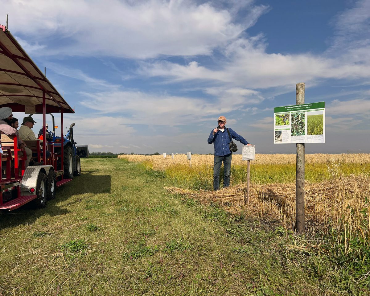 Dr Martin Entz gives a lecture to a wagon of people at the edge of a field.