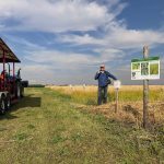 Dr Martin Entz gives a lecture to a wagon of people at the edge of a field.