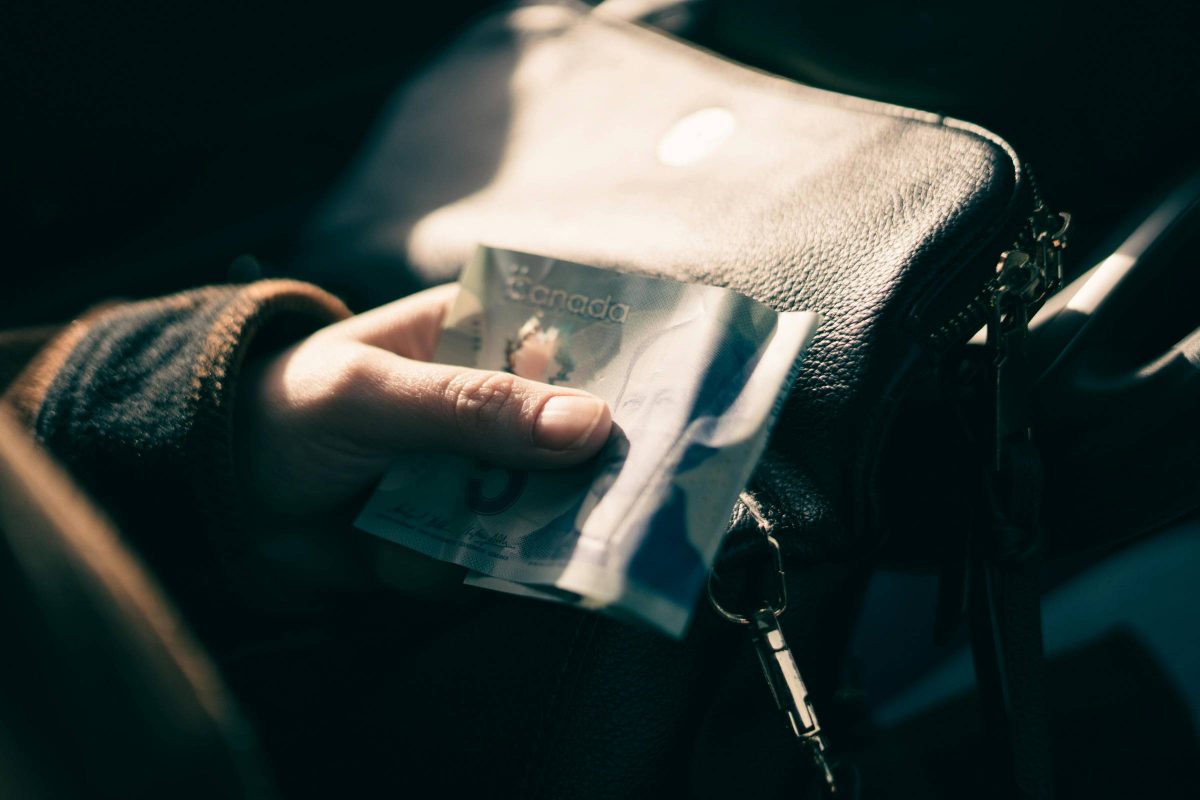 A person holding a five dollar bill in their hands. Photo credit: Erik Mclean