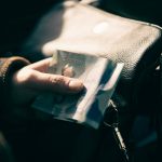 A person holding a five dollar bill in their hands. Photo credit: Erik Mclean