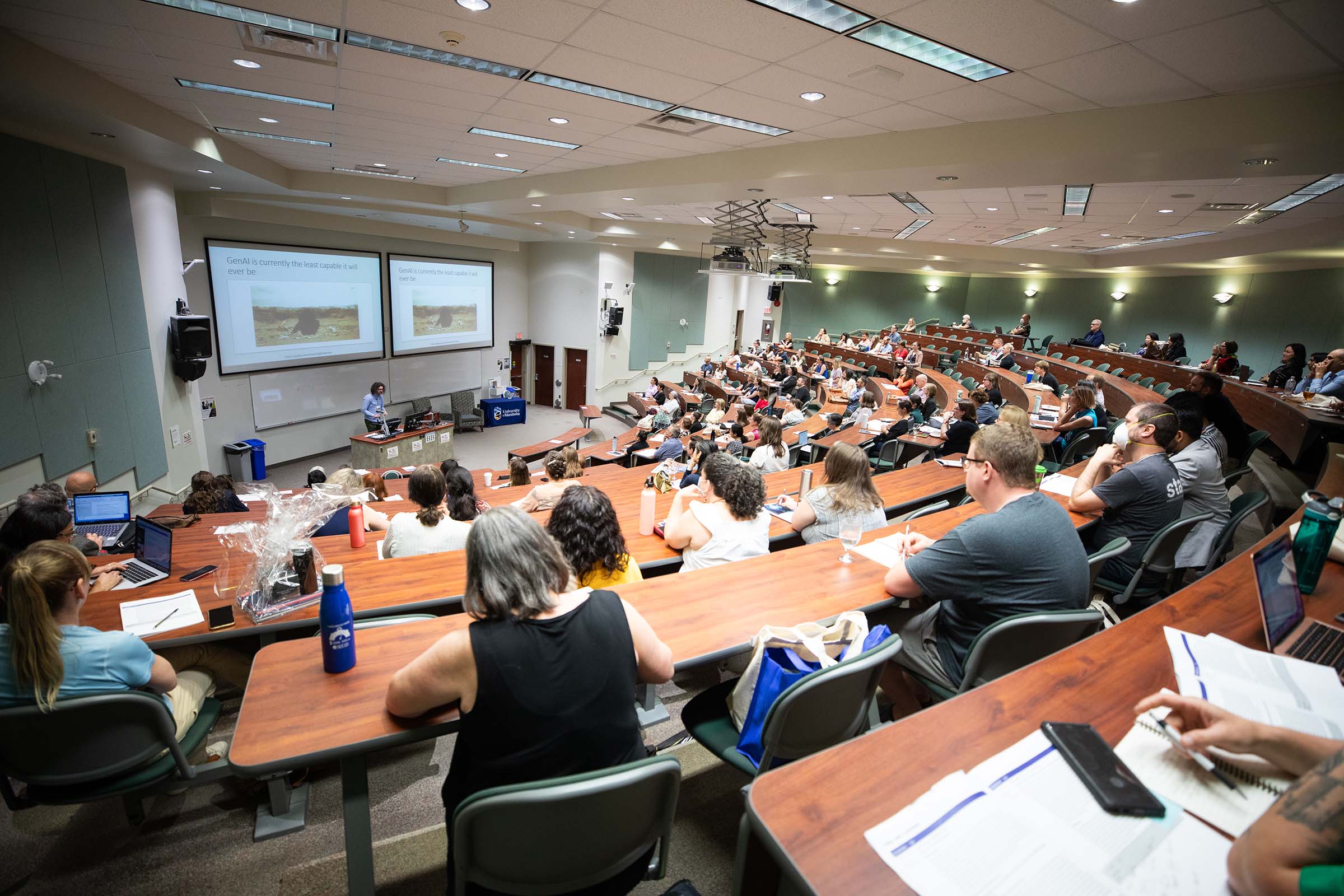 Learners sit in a lecture room, facing a presenter.