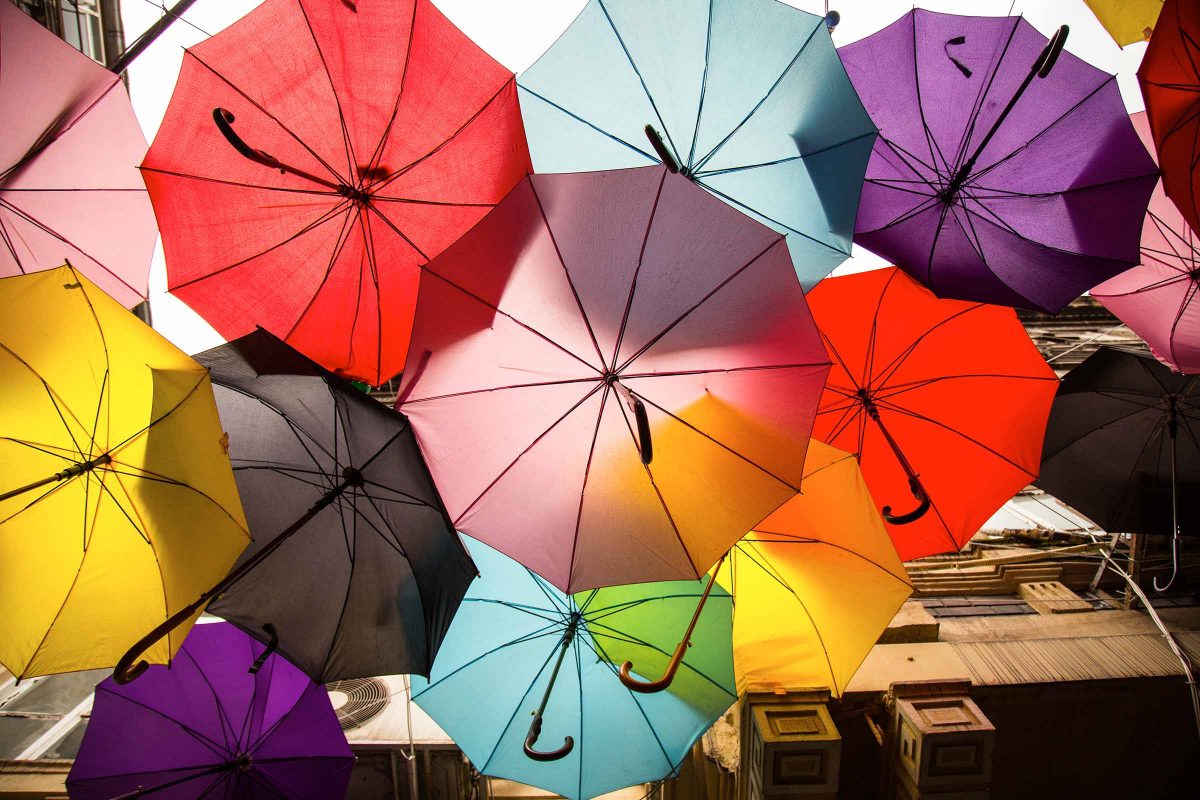 Light filtering through multiple colourful umbrellas.