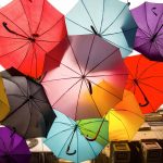 Light filtering through multiple colourful umbrellas.