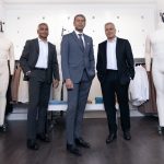 Raj Bahl, Ash Modha and Prashant Modha stand among clothing racks and mannequins in their retail space