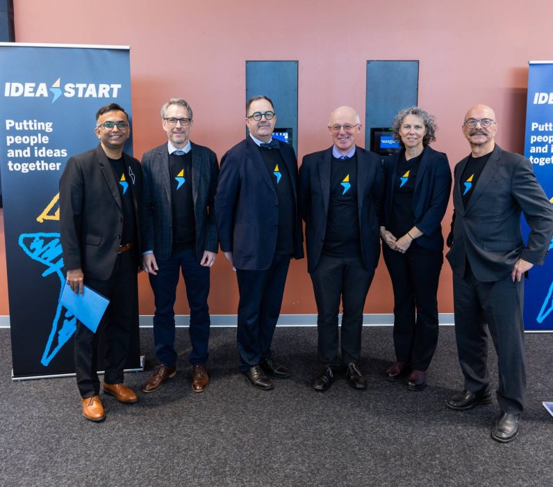 Idea Start community leaders pose together wearing t-shirts featuring the new gold and blue Idea Start lightening bolt logo. 