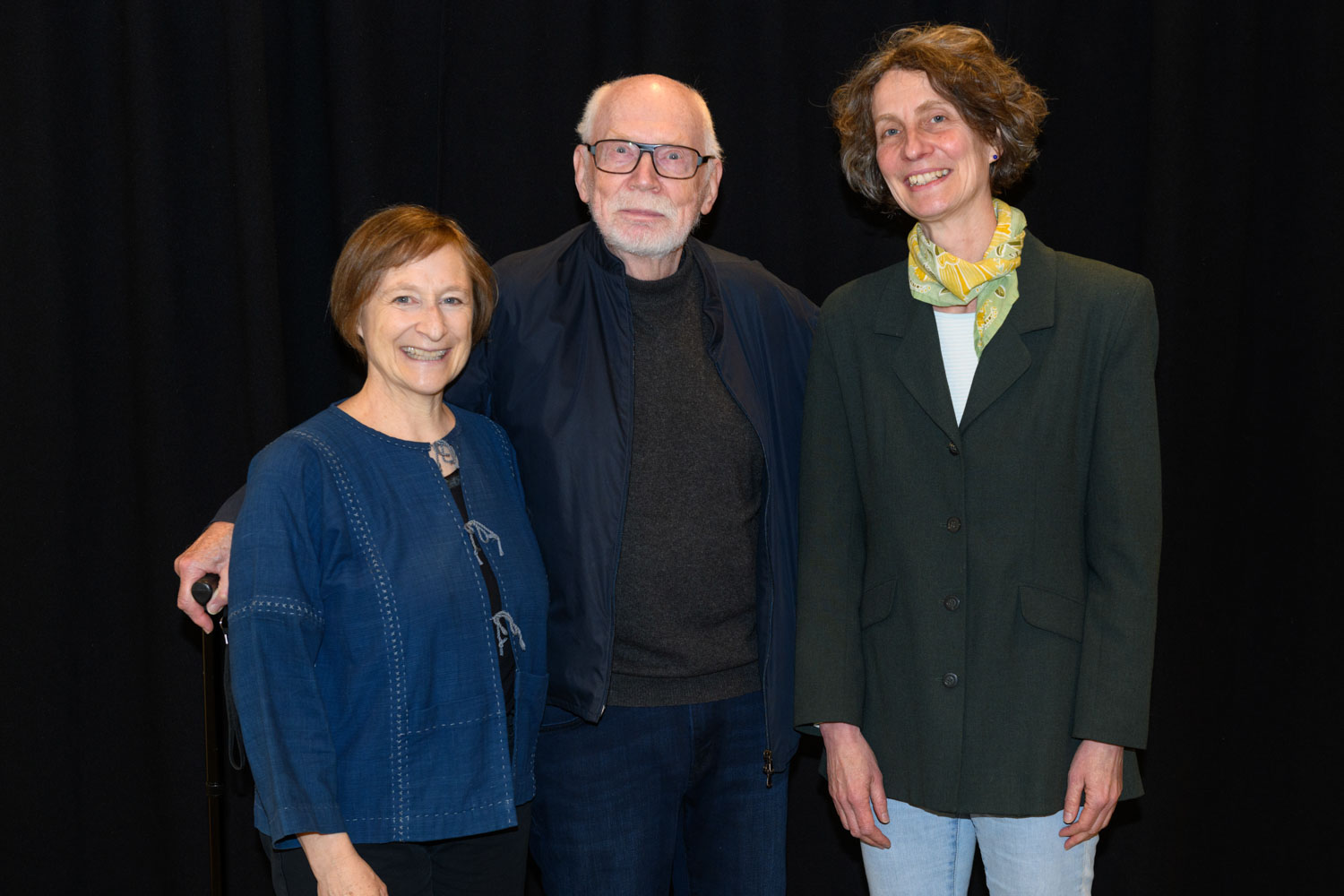 3 individuals dressed in dark colors smiling at the camera