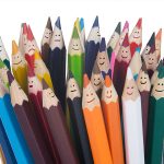 Photo of a group of coloured pencils with happy faces on them.