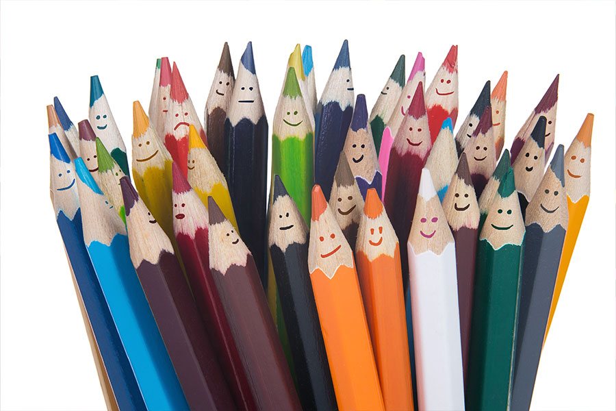 Photo of a group of coloured pencils with happy faces on them.