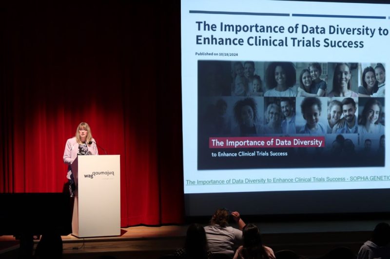 Dr. Laura Saward speaks at a podium beside a projected slide dealing with diversity in clinical trials.