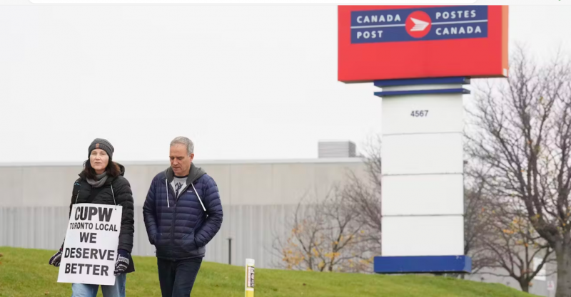 man and woman walking in front of Canada Post sign