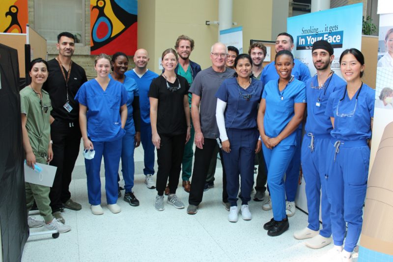 15 people wearing scrubs pose for the photo.