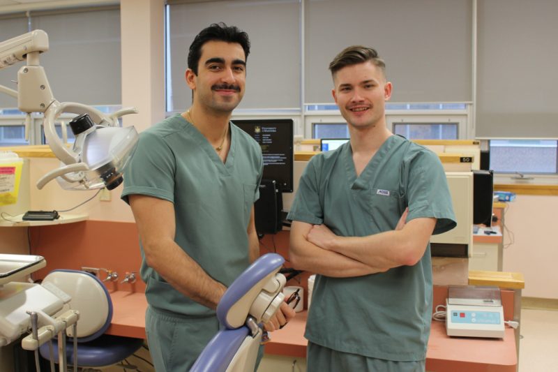 Two students pose for a photo in a dental clinic.