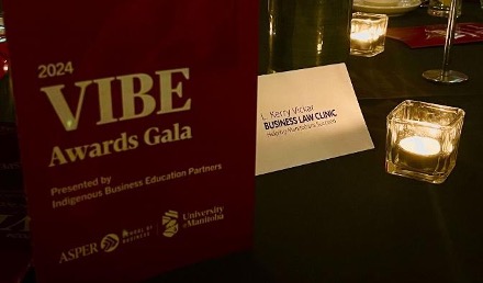 Photo of 2024 VIBE Awards Gala program on table top beside tent card of L. Kerry Vickar Business Law Clinic