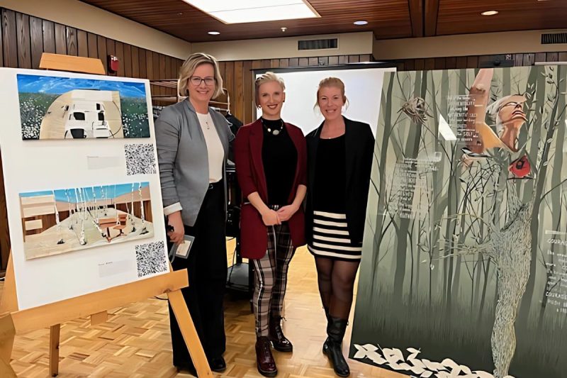 student and research advisors standing with research project display