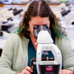 Dr. Cassandra Debets behind a microscope.