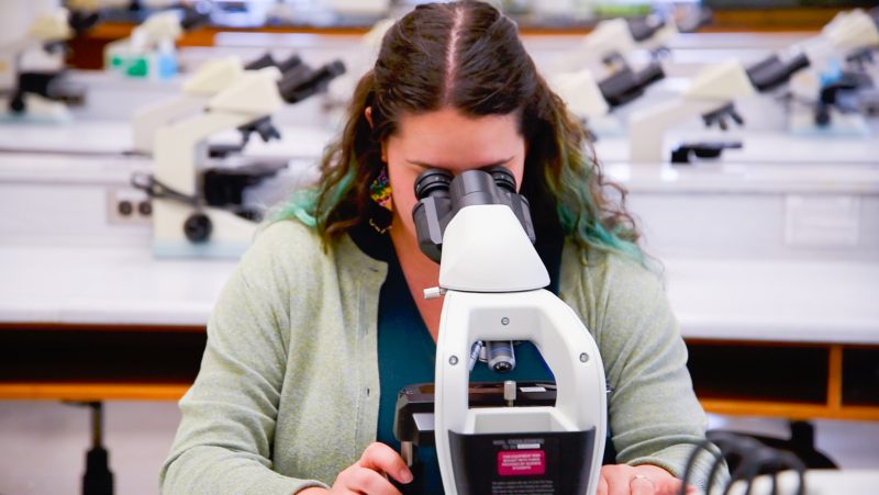 Dr. Cassandra Debets behind a microscope.