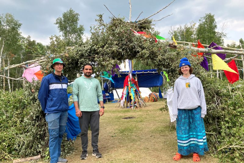 Three students stand in front of a sundance lodge.