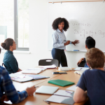 woman teaching math on whiteboard to students