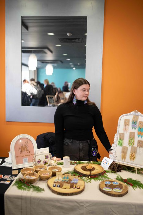 Student with collection of beadwork displayed on table.