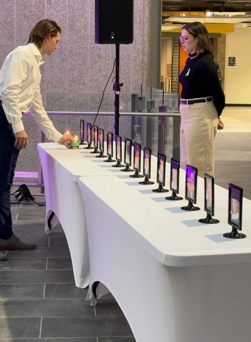 A student placing a lit candle in front of a photo