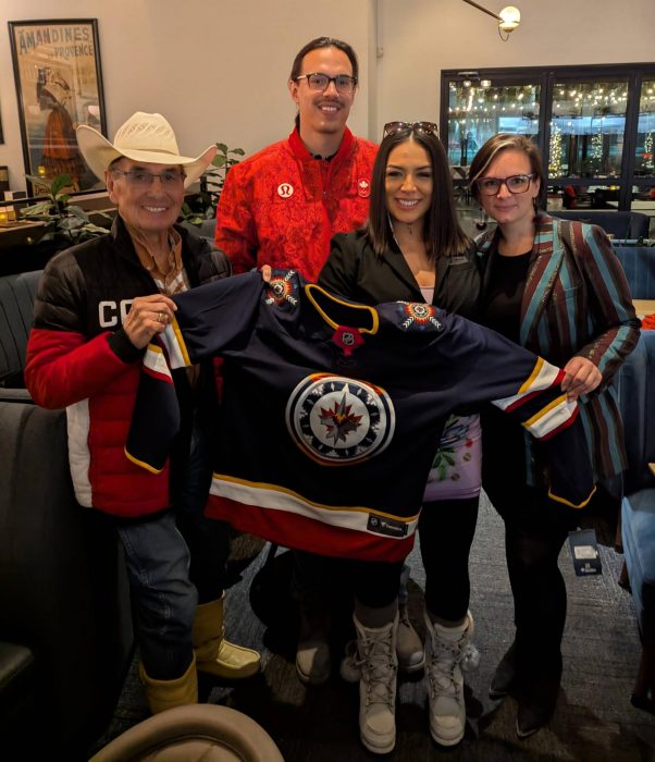 Past and present members of MILSA present Chief Wilton Littlechild, with a Winnipeg Jets WASAC (Winnipeg Aboriginal Sports Achievement Centre) Jersey.