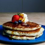 Maple syrup being poured on a stack of pancakes (photo by Sydney Troxell)