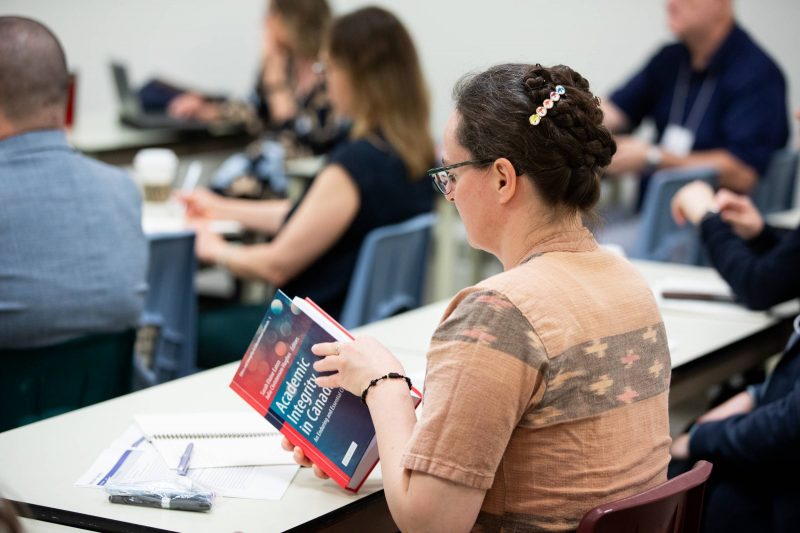 Person reading a book on academic integrity in Canada