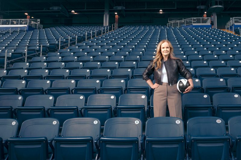 Christina Litz faces the camera, standing in the seats of the stadium