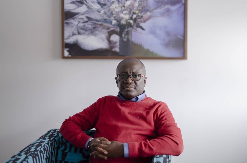 Edmund Opoku-Agyeman sitting on a couch in front for his portrait