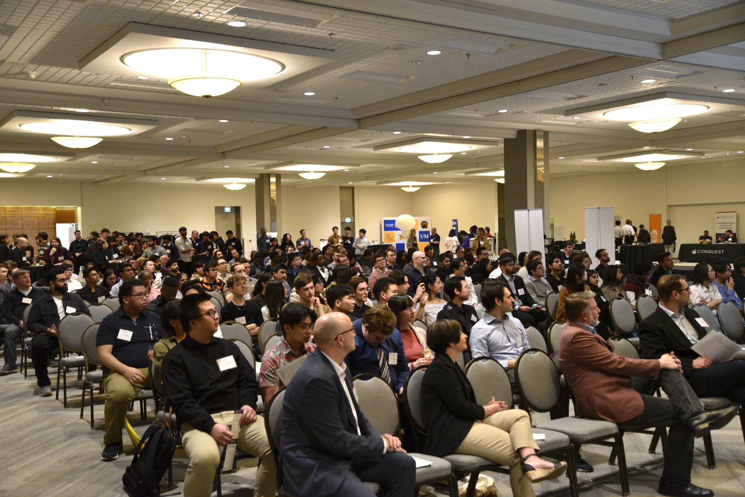 Audience sitting on chairs in a large room paying attention to the presenter.