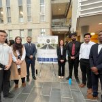 a group of professional looking students posing by poster project