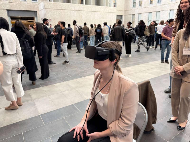 A student is sitting in an event space with a VR headset on