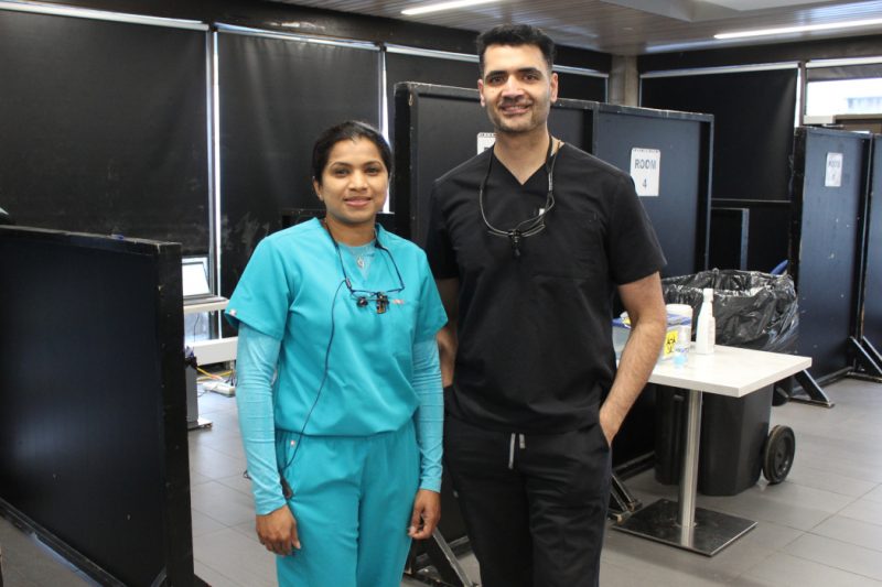 Two dental specialists pose for a photo in a makeshift dental clinic.
