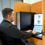 Hamid Hadipour, data scientist sitting behind a desk looking at protein structures on his screen.