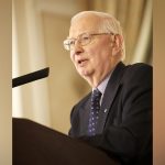 Dr. Henry Friesen speaking at a podium.