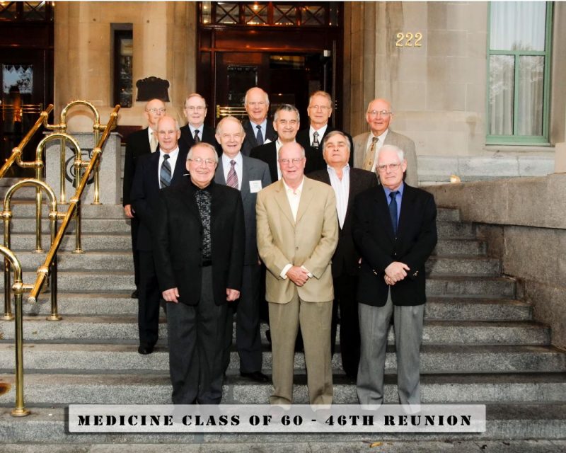 Twelve members of the UM Medicine Class of 1960 stand on an outdoor stairway.