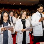 Medical students wearing white coats read the Physician's Pledge.