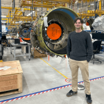 A person standing in a warehouse in front of a large turbine engine